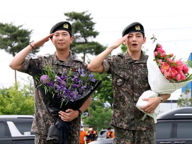 K-pop band BTS's members RM (L) and V (R) react after being discharged from a mandatory military service